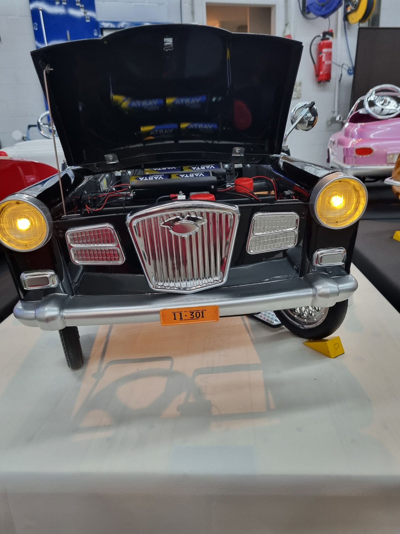 Auf einem Tisch steht ein Spielzeugauto mit geöffneter Motorhaube.